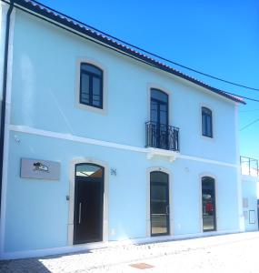 Edificio blanco con puertas negras y balcón en Pinhal Litoral en Marinha Grande