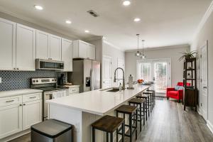 a kitchen with white cabinets and a large island with bar stools at Updated Greenville Home with Deck about 1 Mi to Downtown in Greenville