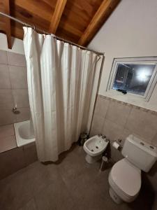 a bathroom with a white shower curtain and a toilet at Enzojo-caviahue in Caviahue
