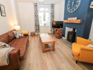 a living room with a couch and a table and a clock at Myrtle Cottage in Morpeth