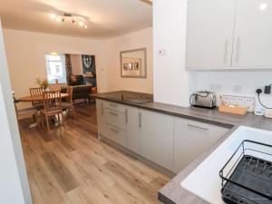 a kitchen with white cabinets and a dining room at Myrtle Cottage in Morpeth