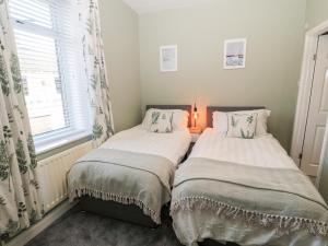 two beds sitting next to a window in a bedroom at Myrtle Cottage in Morpeth