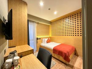 a room with a bed and a desk and a television at Mihman Hotel in Tuzla
