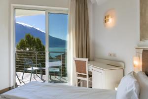 リモーネ・スル・ガルダにあるHotel Sogno del Benacoのベッドルーム1室(ベッド1台付)、景色を望むバルコニーが備わります。