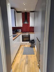 a kitchen with white cabinets and a wooden floor at Stunning 3-Bed House in Manchester in Manchester