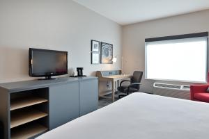 Cette chambre comprend un lit, une télévision et un bureau. dans l'établissement Country Inn & Suites by Radisson, Bloomington-Normal Airport, IL, à Bloomington