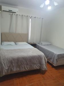 a bedroom with two beds and a wooden floor at Pousada Tia Zane in Pomerode