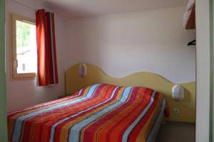 um quarto com uma cama com um cobertor listrado colorido em maisonnette 6 pers dans résidence avec piscine em Arès