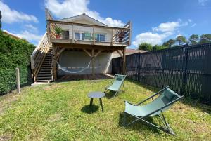 una casa con hamaca y 2 sillas en el patio en APPARTEMENT DES PIGNONS à LEGE BOURG, en Lège-Cap-Ferret