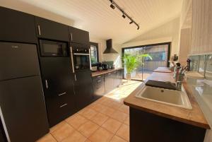 - une cuisine avec des placards noirs et un évier dans l'établissement VILLA ALHENA à Lège Bourg, à Lège-Cap-Ferret