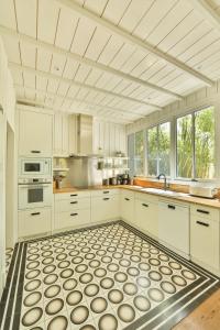 una cucina con armadietti bianchi e pavimento piastrellato di CABANE JASMIN au CAP FERRET a Cap-Ferret