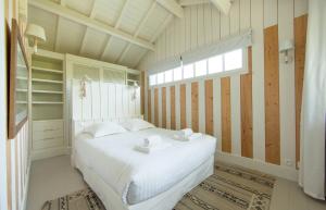 ein Schlafzimmer mit einem weißen Bett und einem Fenster in der Unterkunft CABANE JASMIN au CAP FERRET in Cap-Ferret