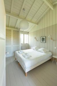 a bedroom with a large white bed in a room at CABANE JASMIN au CAP FERRET in Cap-Ferret