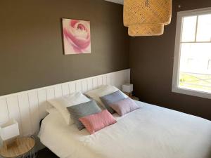 a bed with three pillows on it in a bedroom at VILLA CARO à ARES - BASSIN D'ARCACHON in Arès