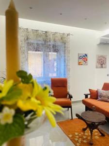 sala de estar con sofá, mesa y flores amarillas en La Pigna Casa Vacanza, en Nicolosi