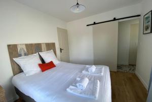 um quarto com uma cama branca e toalhas em VILLA DES BECASSES - Andernos les Bains em Andernos-les-Bains