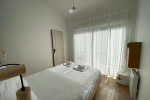 um quarto branco com uma cama e uma grande janela em VILLA DES BECASSES - Andernos les Bains em Andernos-les-Bains
