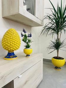 drei gelbe Vasen auf einem Regal mit Pflanzen in der Unterkunft La Pigna Casa Vacanza in Nicolosi