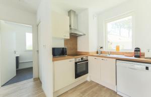 uma cozinha com armários brancos e uma janela em APPARTEMENT Des Verdiers em Andernos-les-Bains