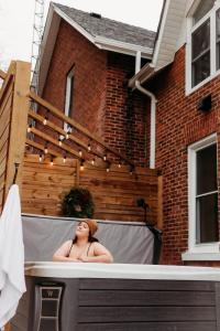 Una donna seduta nella vasca da bagno di fronte a una casa di Lakeview Luxury Farmhouse Retreat - Hot Tub - Games Room a Cobourg