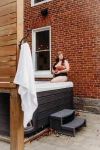 Una donna seduta sul bordo di una vasca da bagno di Lakeview Luxury Farmhouse Retreat - Hot Tub - Games Room a Cobourg