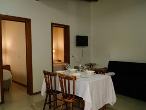 a dining room table with a white table cloth and chairs at Pousada Calmar in Praia do Rosa