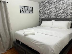 a large bed in a bedroom with a brick wall at NEwark Airport Elegant 3 Kings APT in Elizabeth
