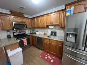 a kitchen with wooden cabinets and stainless steel appliances at NEwark Airport Elegant 3 Kings APT in Elizabeth