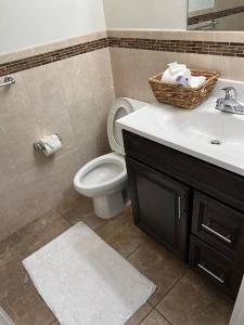 a bathroom with a toilet and a sink with a basket at NEwark Airport Elegant 3 Kings APT in Elizabeth