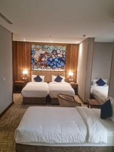 una habitación de hotel con 3 camas y un cuadro en la pared en EWG Golden Sea Hotel Obhur en Yeda