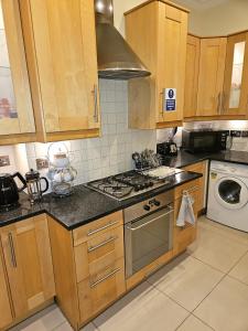 a kitchen with wooden cabinets and a stove top oven at HEATHROW MANSION SHUTTLES in Uxbridge