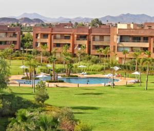 un complexe avec une piscine et un grand bâtiment dans l'établissement Appartement de Luxe Prestigia, à Marrakech