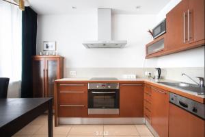 a kitchen with wooden cabinets and a stove top oven at Spacious Quiet Apt Close to the Belvedere Palace in Warsaw