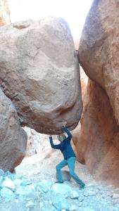 Un homme grimpe à un rocher dans un canyon dans l'établissement Maison D'hote Amazir, à Boumalne