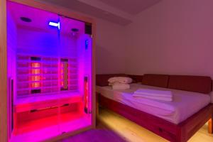 Cette chambre comprend un lit et une lumière LED rose. dans l'établissement Vilaraj, à Maribor
