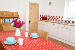 een keuken met een tafel met een vaas met bloemen erop bij Coach House Barn in Cranleigh