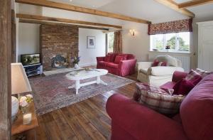 a living room with red furniture and a fireplace at Coach House Barn in Cranleigh