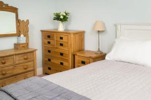 a bedroom with a bed and a dresser and a mirror at Coach House Barn in Cranleigh