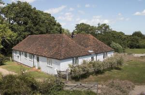 an old white house with a brown roof at Coach House Barn in Cranleigh