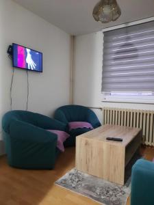 een woonkamer met twee blauwe stoelen en een tafel bij Apartment Lamele Bugojno in Bugojno