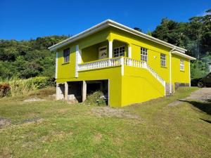 Casa amarilla con balcón en la parte superior de un patio en Tim's & Mag's Home Stay, en Roseau