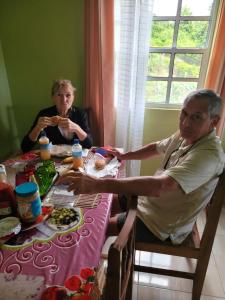 dos personas sentadas en una mesa comiendo comida en Tim's & Mag's Home Stay, en Roseau