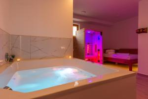 La salle de bains est pourvue d'une grande baignoire avec des lumières violettes. dans l'établissement Vilaraj, à Maribor
