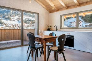 een keuken met een houten tafel en stoelen en uitzicht bij Lena Dolomites Luxury Suite in Villnoss