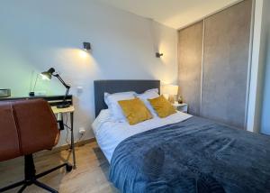 a bedroom with a bed with yellow pillows and a desk at Meublé classé 3 étoiles Centre Ville de Céret in Céret