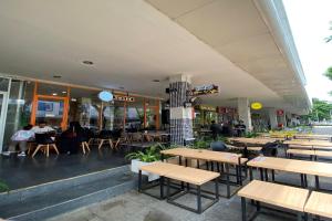 un restaurant avec des tables en bois et des personnes assises à table dans l'établissement Hariss Inn Bandara, à Teko