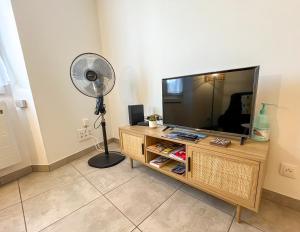 a living room with a flat screen tv and a fan at Meublé classé 3 étoiles Centre Ville de Céret in Céret