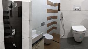 a white bathroom with a toilet and a sink at Royal Home in Kuravalangād