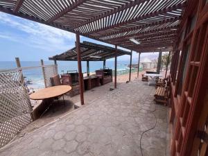 a patio with a table and benches on the beach at Hotel Josefina in Alto Hospicio