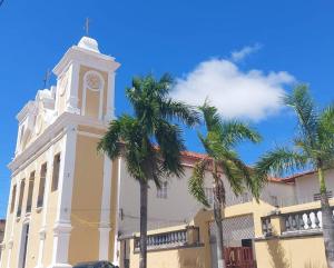a building with a clock tower and palm trees at Will's House in São Luís